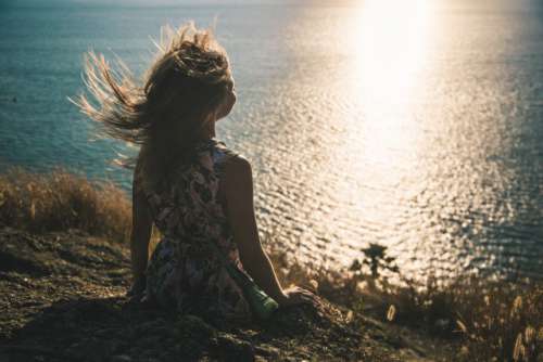 Girl watching sunset and wind playing with her hair 