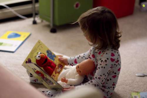 Toddler reading to her baby 