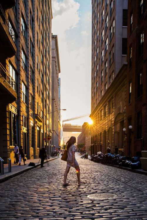 golden sun backlights in brooklyn with girl crossing street