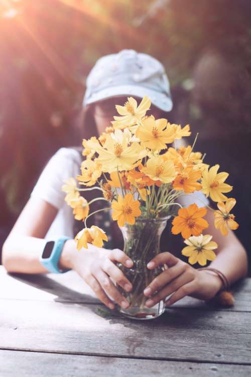 A girl holding a vase with flowers outdoor 