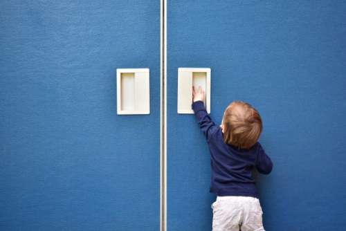 Cute baby boy trying to open blue door
