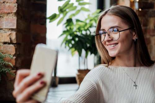 Happy woman in eyeglasses doing selfie