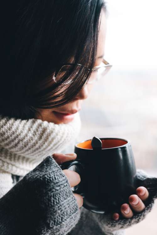girl in sweater holding a hot cup of drink