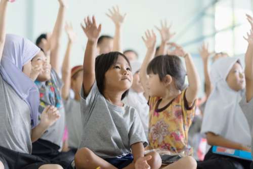 Group of asian kids raise hand up at school.