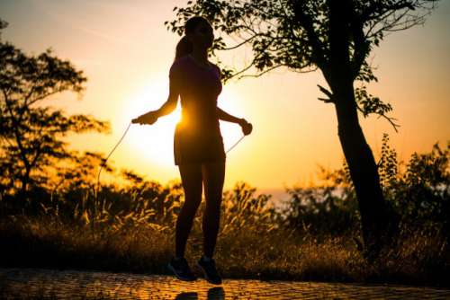 Silhouette of Girl jumping over a rope in sunrise light