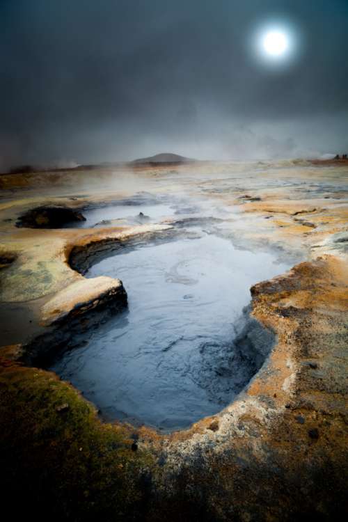 Hverir, iceland. Hot mud acid pool with dramatic landscape with full moon in the fog
