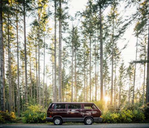 A maroon Volkswagen Vanagon sits in the sunset light