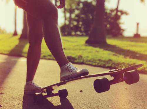 Woman cruising on a longboard in a park 