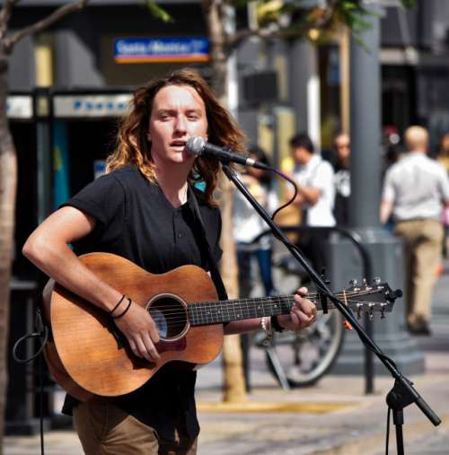 Nominated- street performer singing and playing a guitar into the microphone on the street at the 3Rd street Promenade in Santa Monica California 