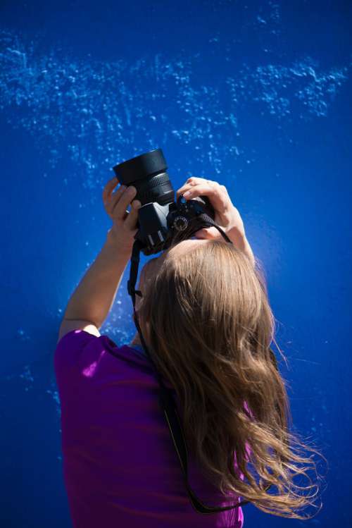 A portrait of a female photographer on a monochrome blue background