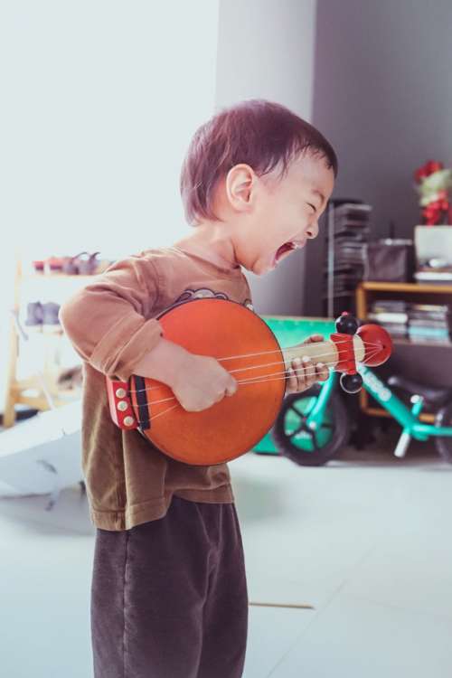 A boy is playing toy guitar.