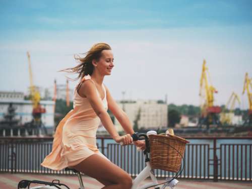 Beautiful young blonde woman riding retro bicycle in marine port