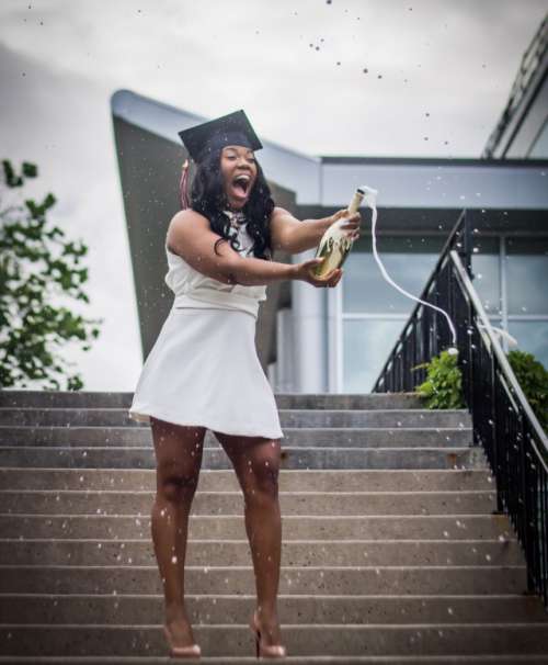 Girl popping champagne bottle after graduation.