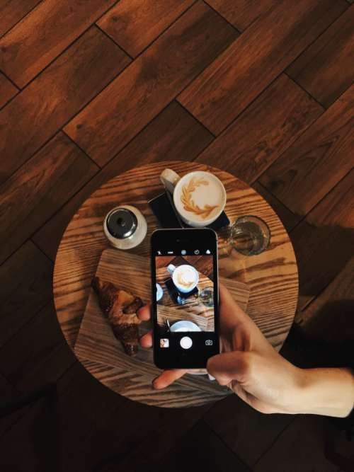Woman taking photo of coffee on mobile device 