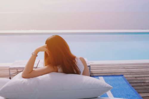 Woman feeling relax on bean bag nearby the swimming pool at the luxury resort