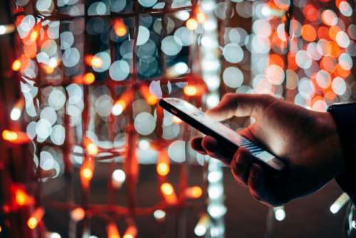 Man using mobile device at colorful light background 