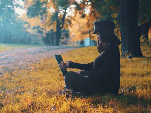 Beautiful woman working on laptop in autumn park 