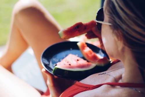 The girl sunbathes and eats watermelon

