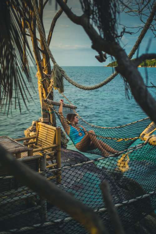 Young woman in a swimsuit laying in the hammock over the sea