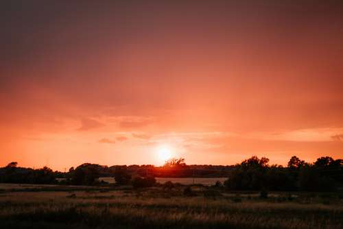 Intense Red Sunset Over Fields Photo