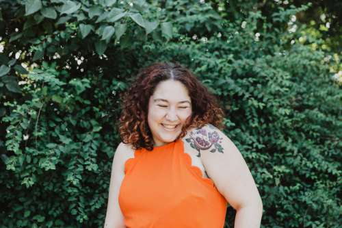 Young Woman In Orange Shirt With Pomegranate Tattoo Photo
