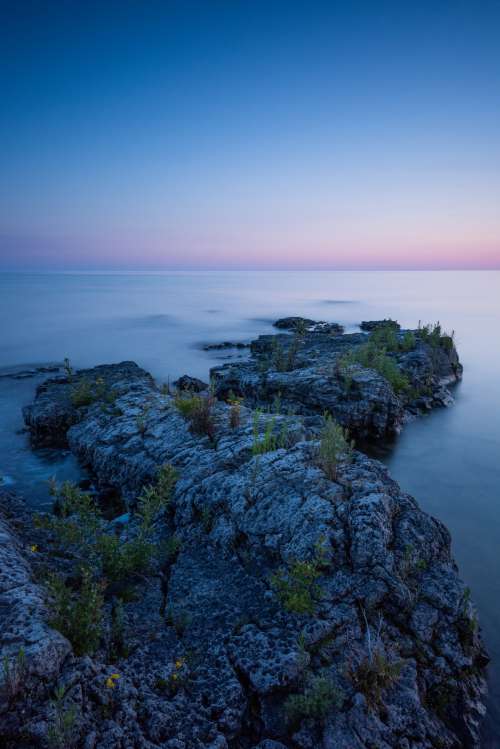 Rock Along Shoreline Leads Out Into Calm Waters Photo