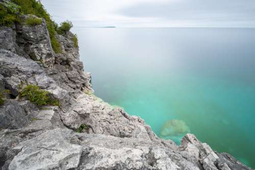 Clear Blue Water At the Bottom Of Rocky Cliffside Photo