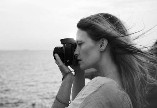 Side view of a young woman taking photograph - black and white