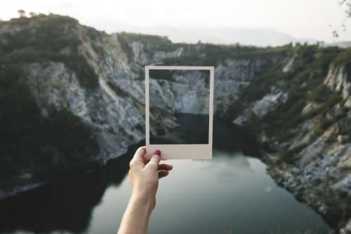 Holding a photo frame shaped paper cut out in front of landscape