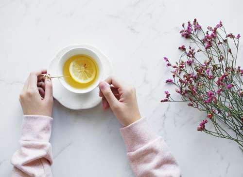 Flat lay of hands holding a lemon tea cup and on saucer