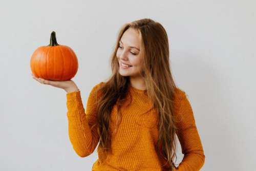 A young girl holds a pumpkin in her hand