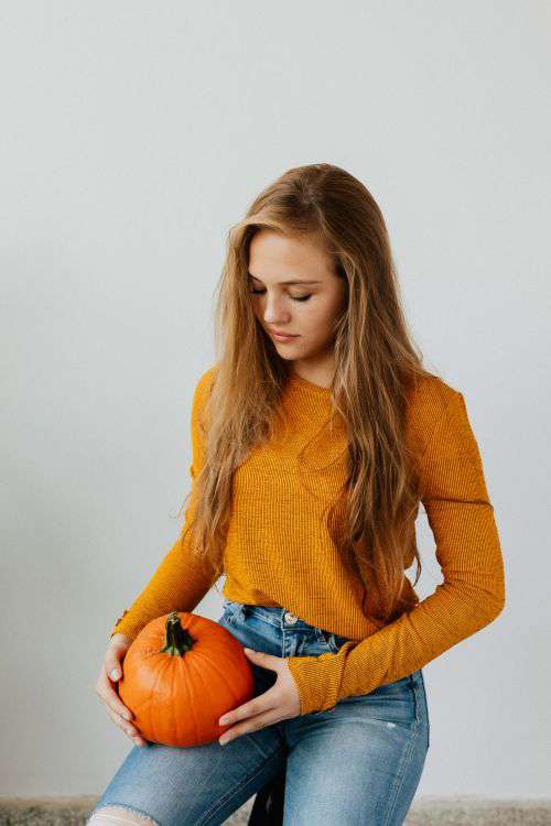 A young girl holds a pumpkin in her hand