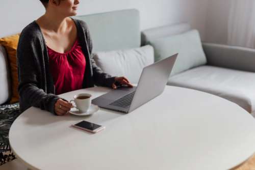 A brunette woman works with a laptop and a phone