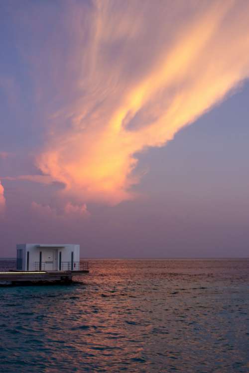 Bungalow on Water with Sunset Sky Behind