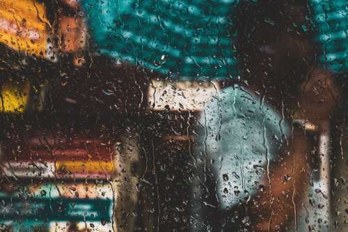 A Person With An Umbrella Through A Rain-Speckled Window Photo