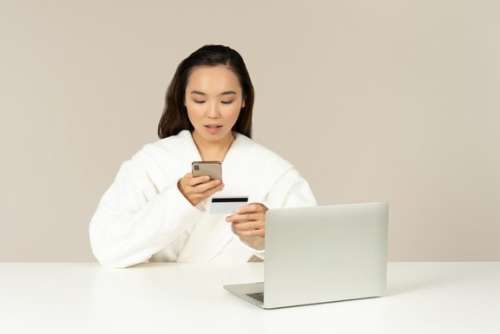 Young Asian Woman Using Phone And Checking Card