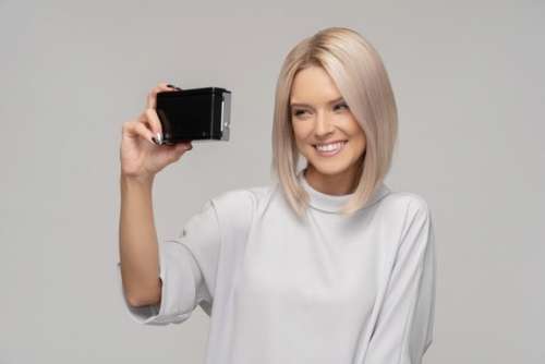 Smiling Young Woman Taking A Selfie With An Old Camera