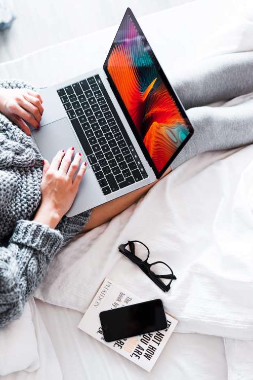 Woman Using Her New MacBook in Bed Free Photo