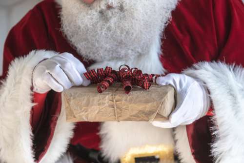 Santa Fixes The Bow On A Gift Photo