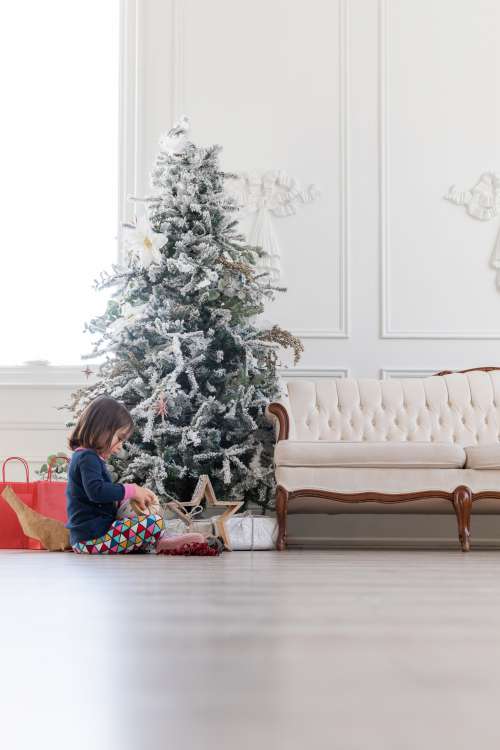 Child Opens Gift Under Christmas Tree Photo