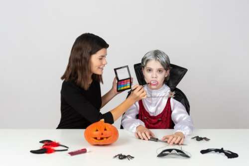 Mom In Cat Costume Making A Make-up To Her Son In Vampire Costume