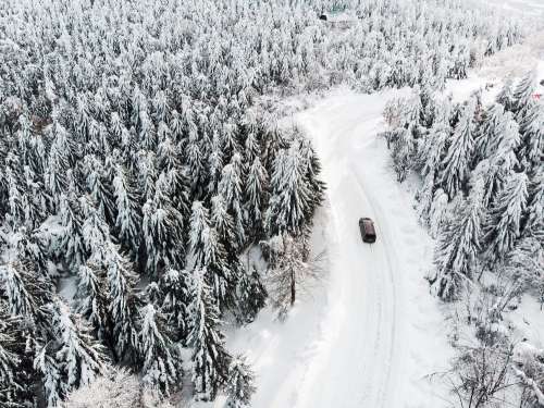 Car Driving on a Snowy Road in The Woods Free Photo