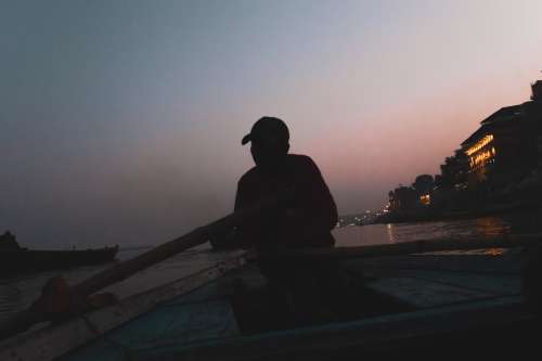 Man Rowing A Boat At Dusk Photo