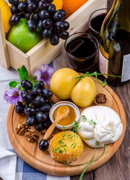 Cheese Plate with black grapes on wooden board