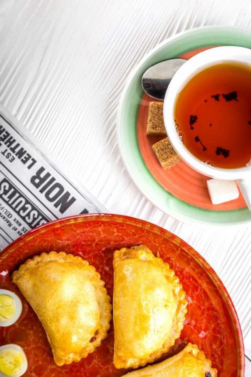 Over head view of a cup of tea and Russian pirozhki baked patties