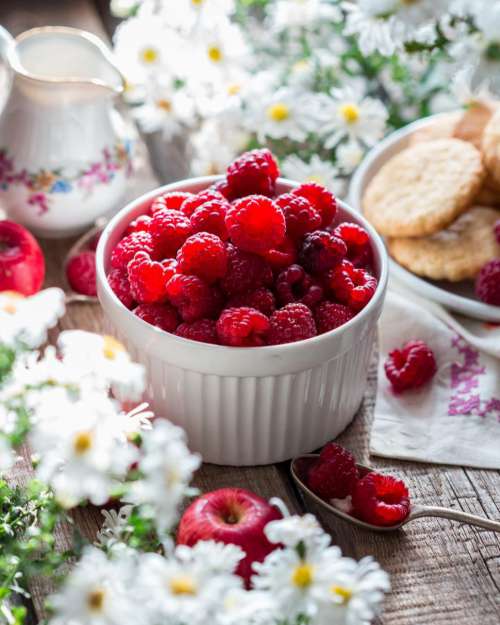 Table with flowers and a bowl of raspberries
