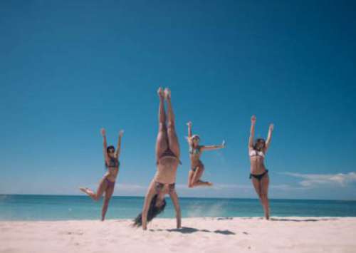 Four Girls In Bikinis Playing On The Beach