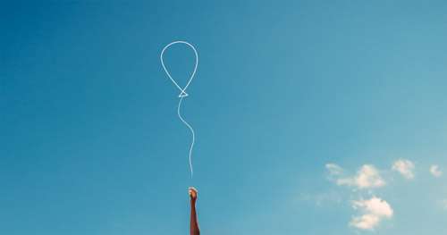 Woman’s Hand Reaching With Hope To Catch A Balloon Against Blue Sky
