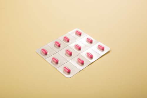 Packaged Pink Pills On Dusty Yellow Photo