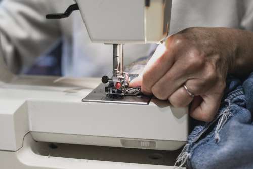 Hand Runs Denim Through Sewing Machine Photo